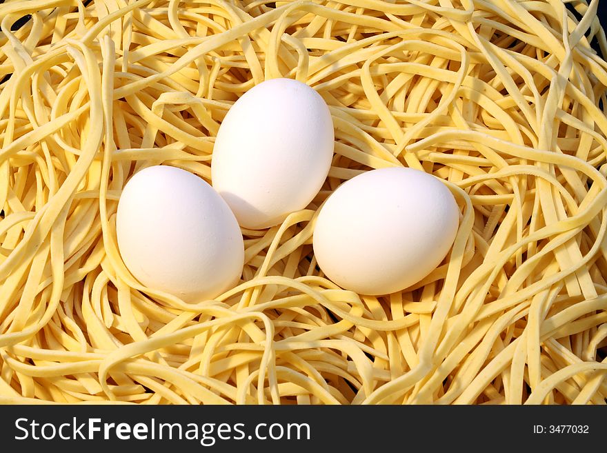 Fresh spaghetti and three white eggs. Fresh spaghetti and three white eggs.