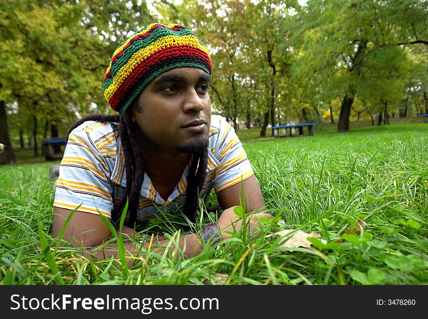 Sad Rastafarian Jamaican thinking laid on grass. Sad Rastafarian Jamaican thinking laid on grass