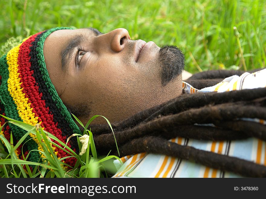 Sad Rastafarian Jamaican thinking laid on grass. Sad Rastafarian Jamaican thinking laid on grass