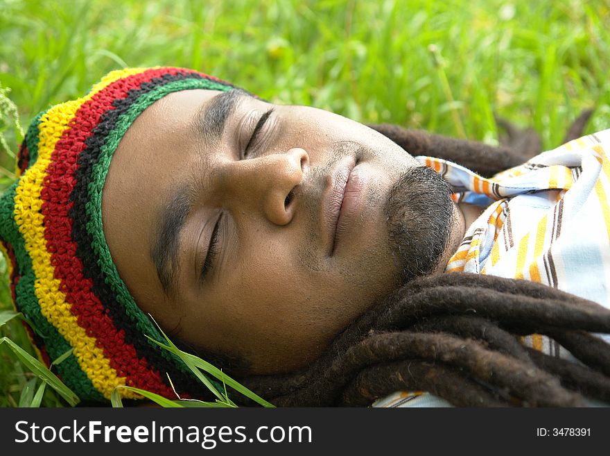 Happy Rastafarian Jamaican sleeping laid on grass. Happy Rastafarian Jamaican sleeping laid on grass