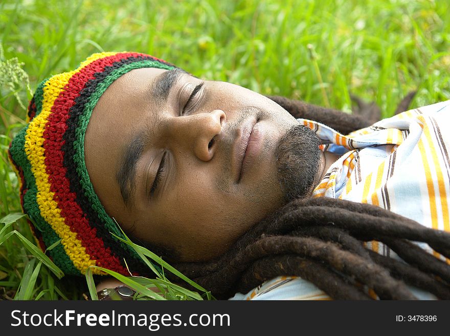 Happy Rastafarian Jamaican sleeping laid on grass. Happy Rastafarian Jamaican sleeping laid on grass