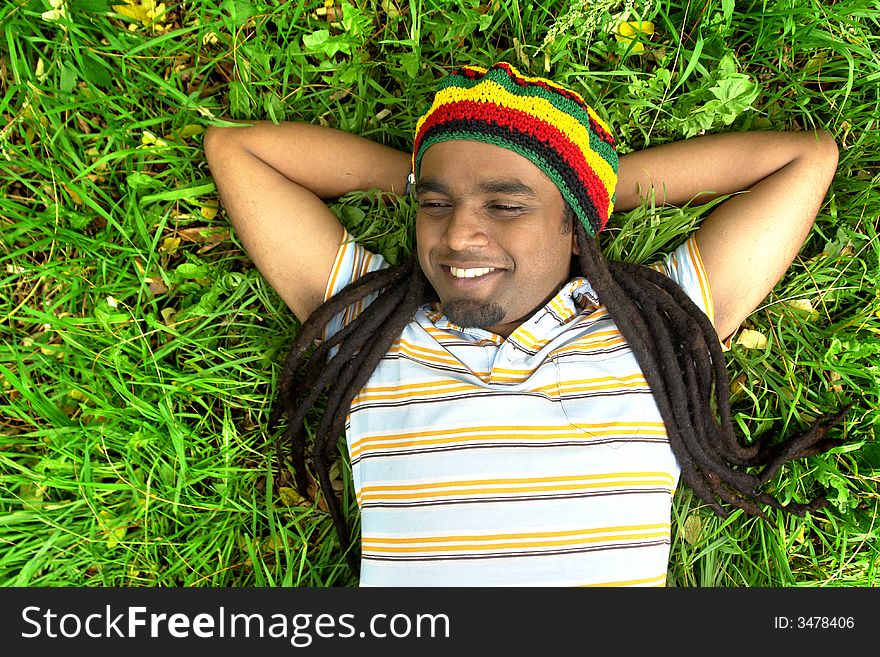 Happy Rastafarian Jamaican smiling laid on grass. Happy Rastafarian Jamaican smiling laid on grass