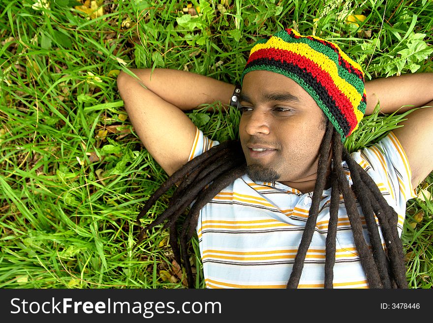 Happy Rastafarian Jamaican smiling laid on grass. Happy Rastafarian Jamaican smiling laid on grass