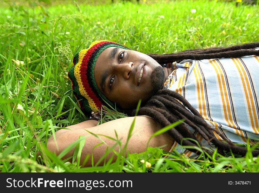 Happy Rastafarian Jamaican smiling laid on grass. Happy Rastafarian Jamaican smiling laid on grass