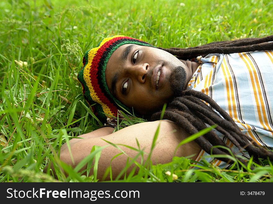 Sad Rastafarian Jamaican thinking laid on grass. Sad Rastafarian Jamaican thinking laid on grass