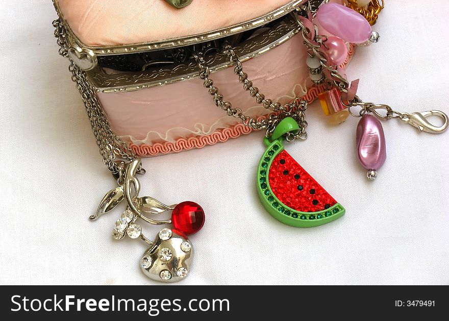 A pink decorated jewellery box filled with jewels