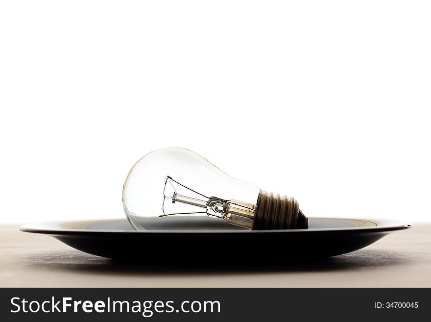 Light bulb served in black plate on table, white background