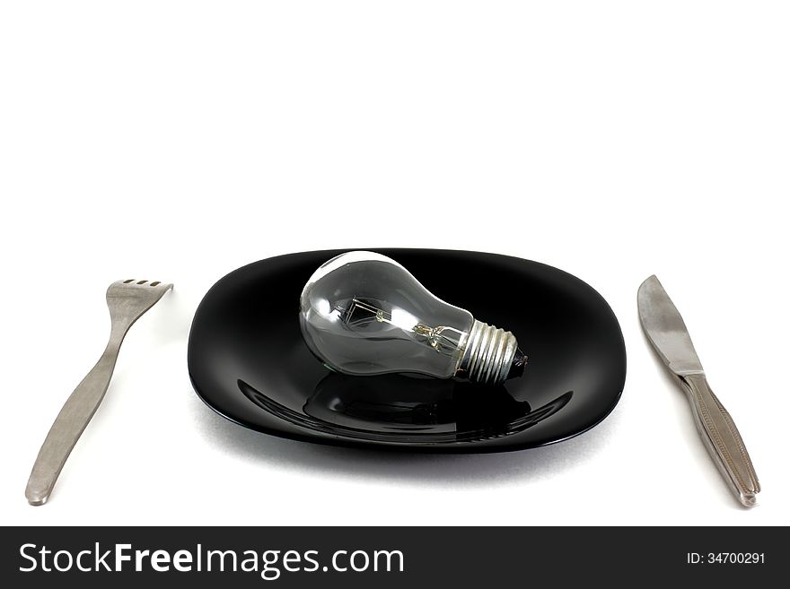 Light bulb in plate and fork and knife on white. Light bulb in plate and fork and knife on white