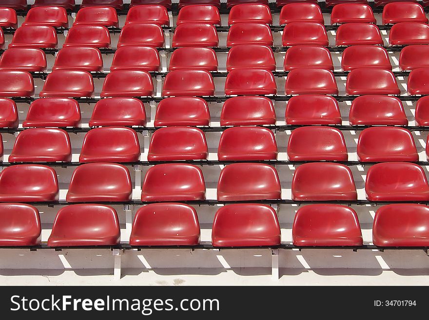 Amphitheater of red seats abstract background in sunlight. Amphitheater of red seats abstract background in sunlight