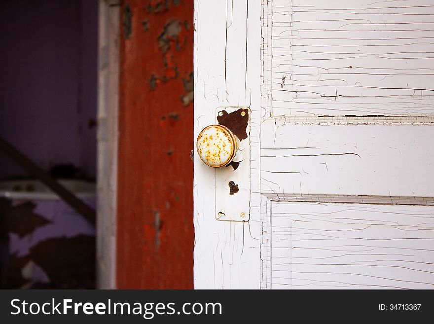 An old doorknob on a weathered white wood door. An old doorknob on a weathered white wood door