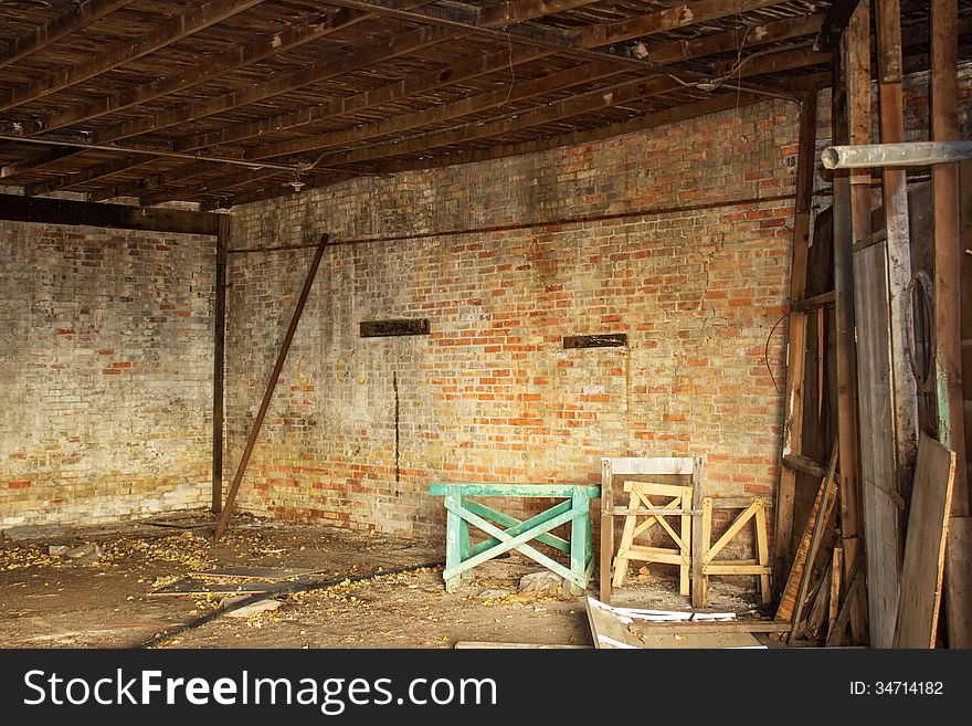 A weathered orange and yellow brick wall and a sawhorse in a abandoned building. A weathered orange and yellow brick wall and a sawhorse in a abandoned building