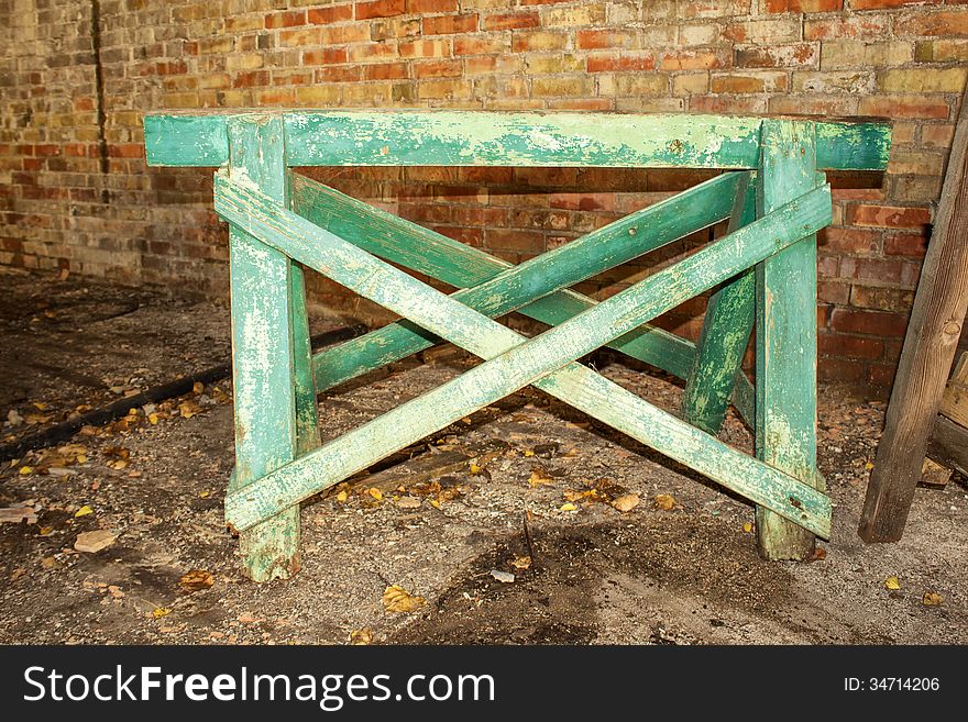 A green sawhorse in front of a brick wall