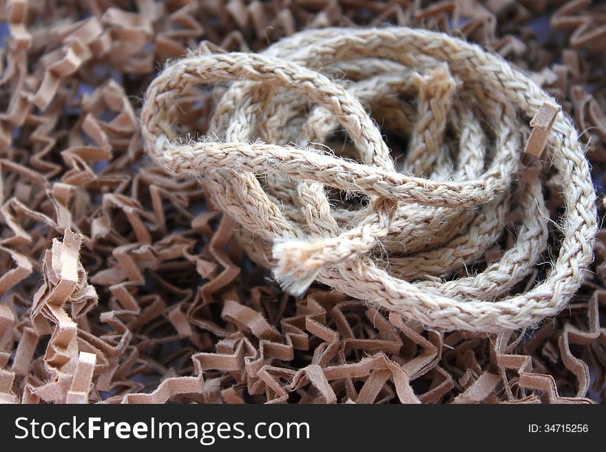A piece of twisted hemp rope on background of textured material. A piece of twisted hemp rope on background of textured material
