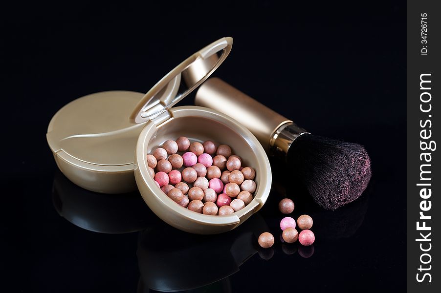 Powder and brush on a black background. Women's cosmetics