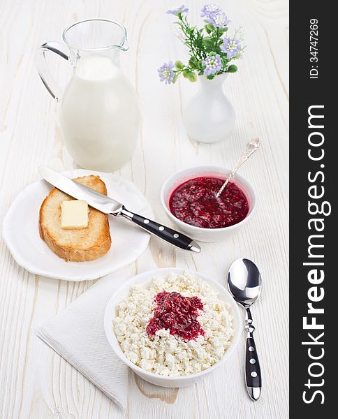 Breakfast with cottage cheese and milk. White wooden background.