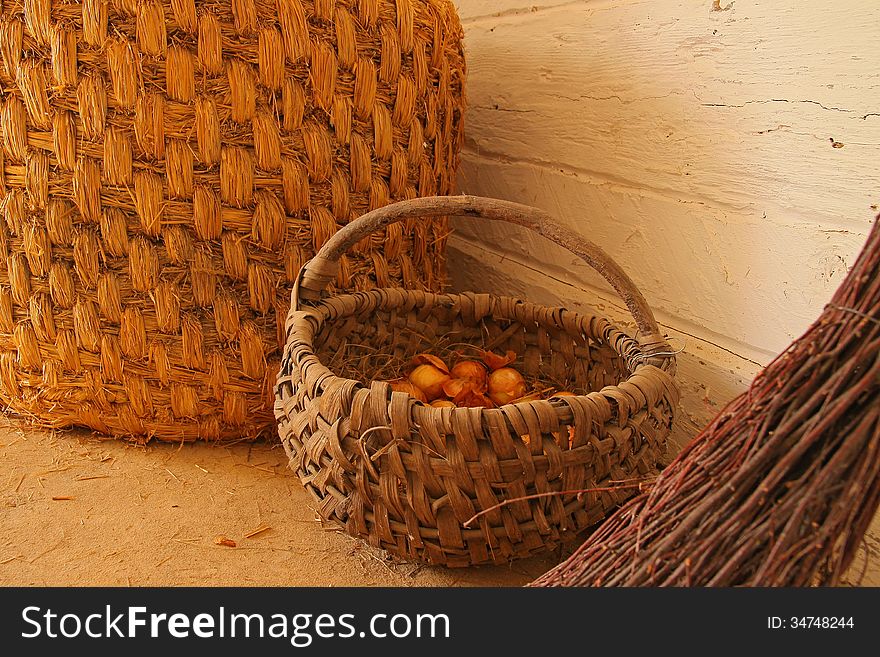 Inside of a wooden cottage: a wicker baskets and a broom