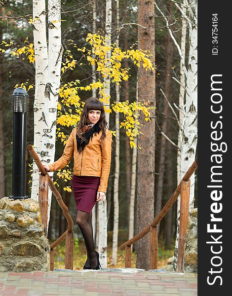 Charming girl in the autumn forest on the stairs