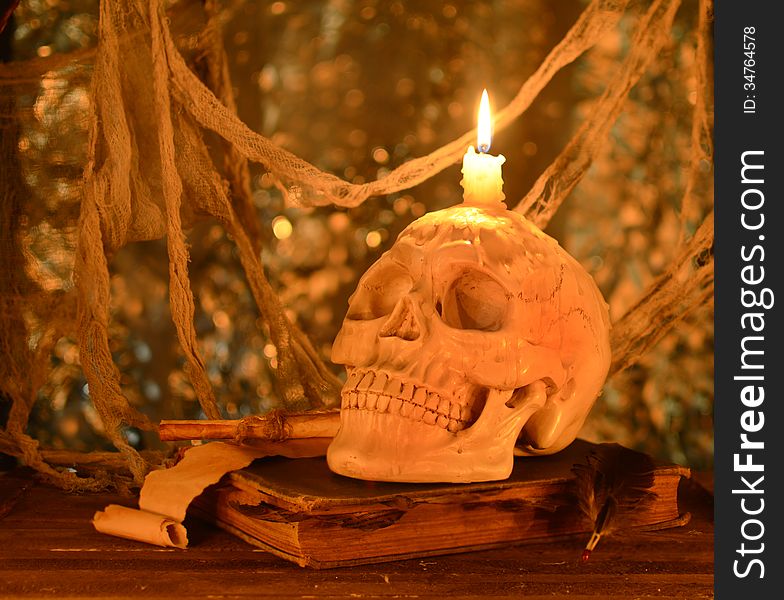 Creepy human skull with burning candle on old book. Creepy human skull with burning candle on old book