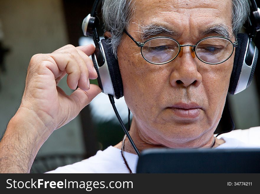 Image of Senior man enjoying music on his tablet