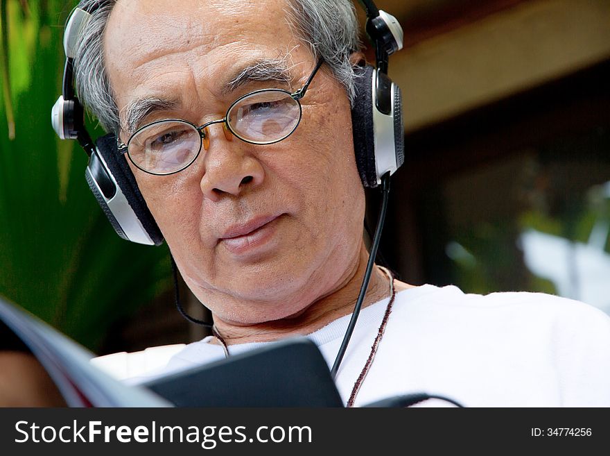 Senior Man Enjoying Music On His Tablet