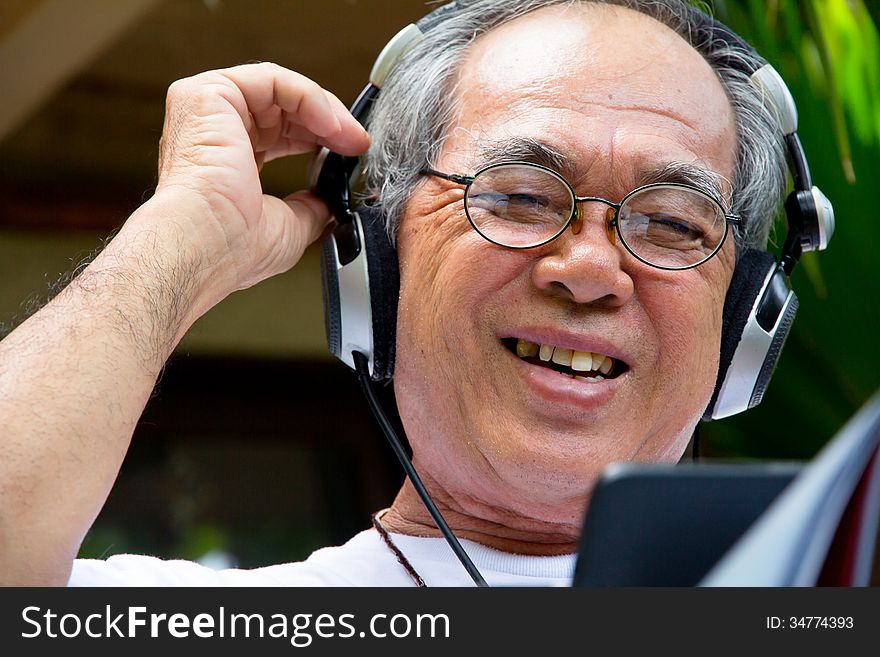 Image of Senior man enjoying music on his tablet