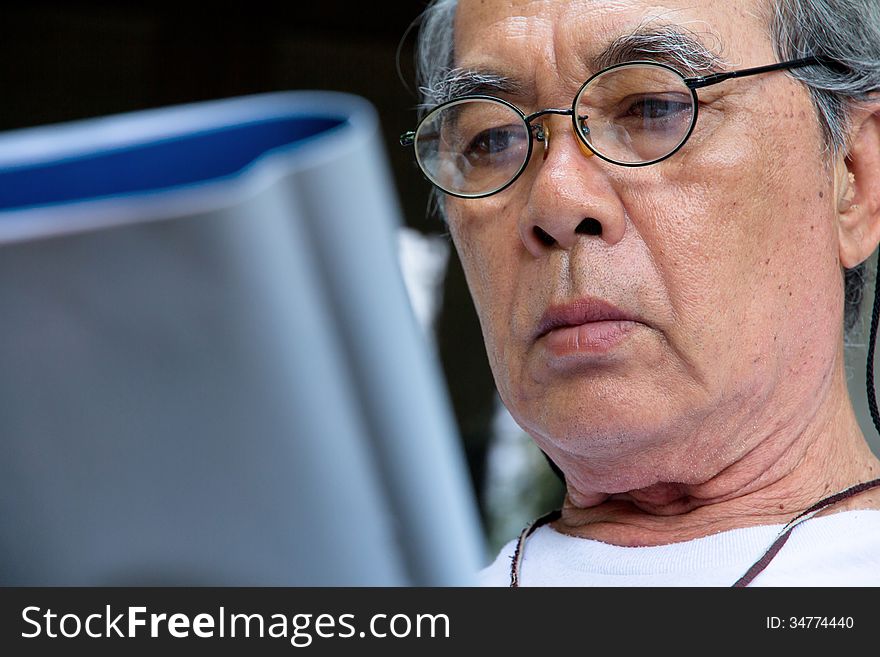 Image of Senior man relaxing at home reading a book