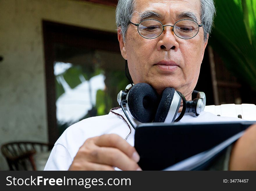 Senior man relaxing at home reading E-book on his tablet