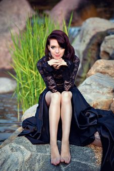 Gorgeous Girl In Black Dress Sitting On A Rock Royalty Free Stock Image