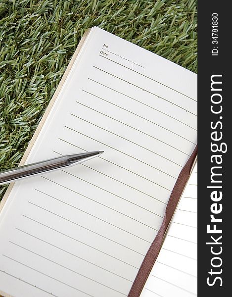 Blank page of notebook with pen on grass. Blank page of notebook with pen on grass