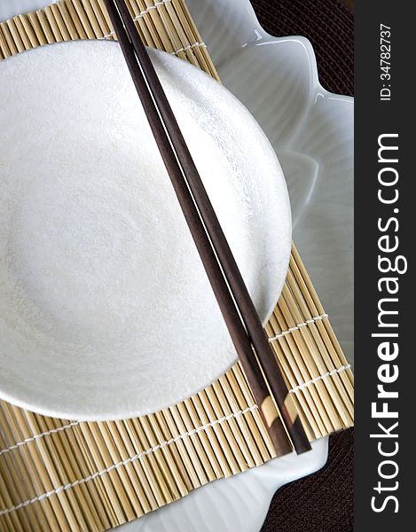 White dish with chopstick on bamboo mat. White dish with chopstick on bamboo mat