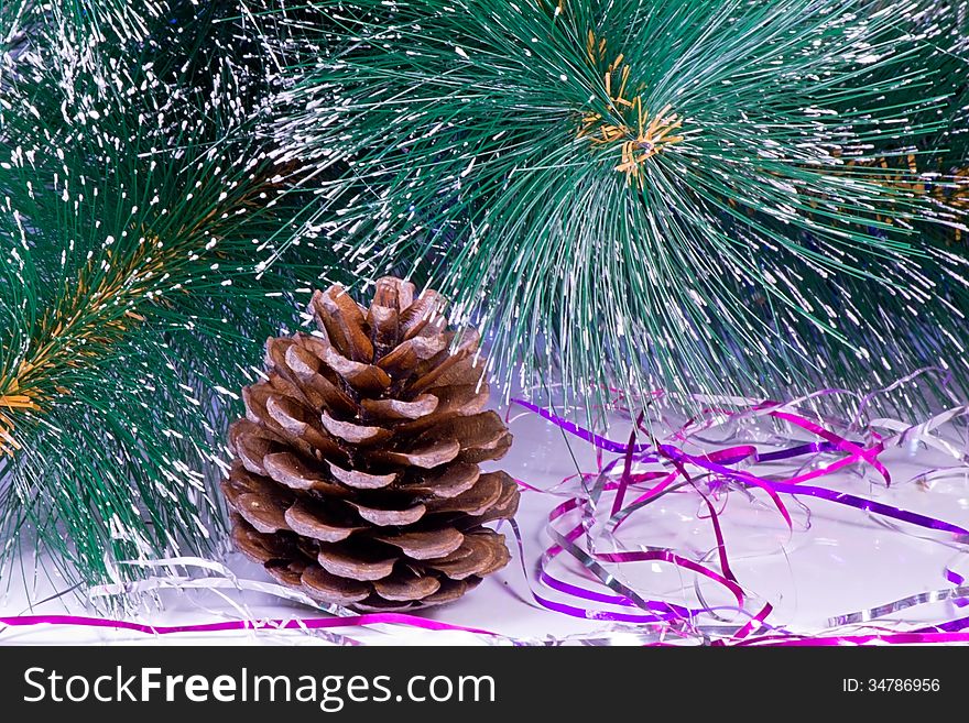 Near the branches of the tree is a pine cone and Christmas decorations. Near the branches of the tree is a pine cone and Christmas decorations