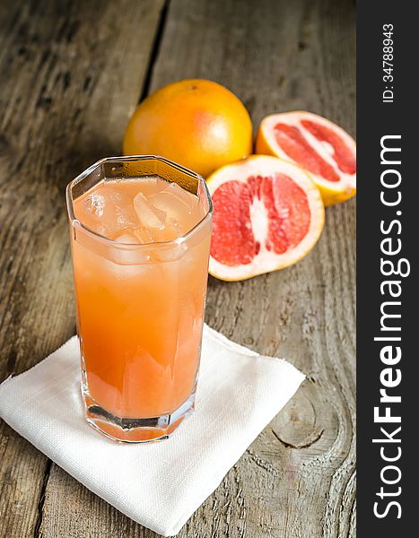 Glass with grapefruit juice and grapefruits