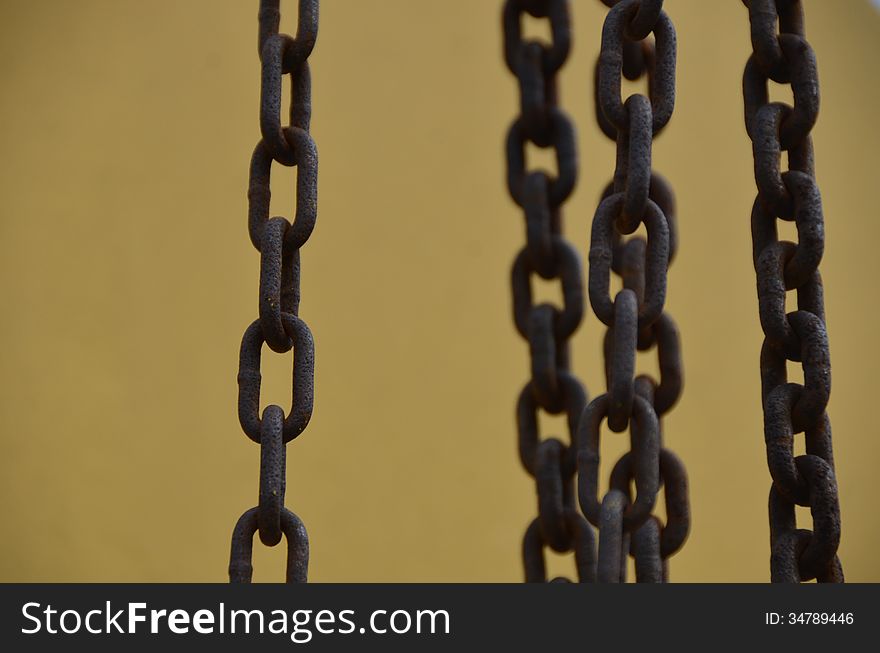 Five rusty chains on a yellow/gold metal background. Five rusty chains on a yellow/gold metal background