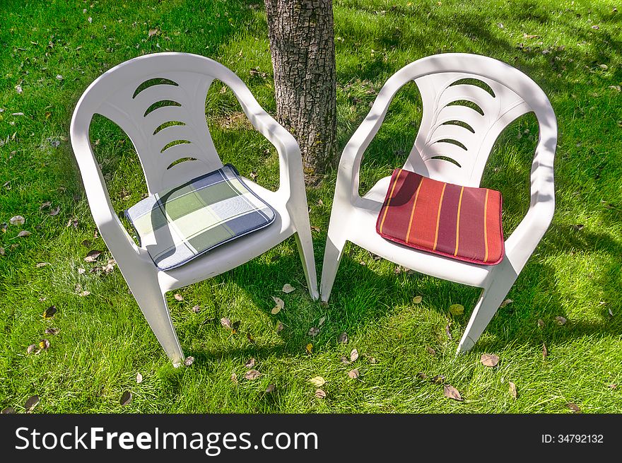 Two empty plastic chairs in the garden. Two empty plastic chairs in the garden