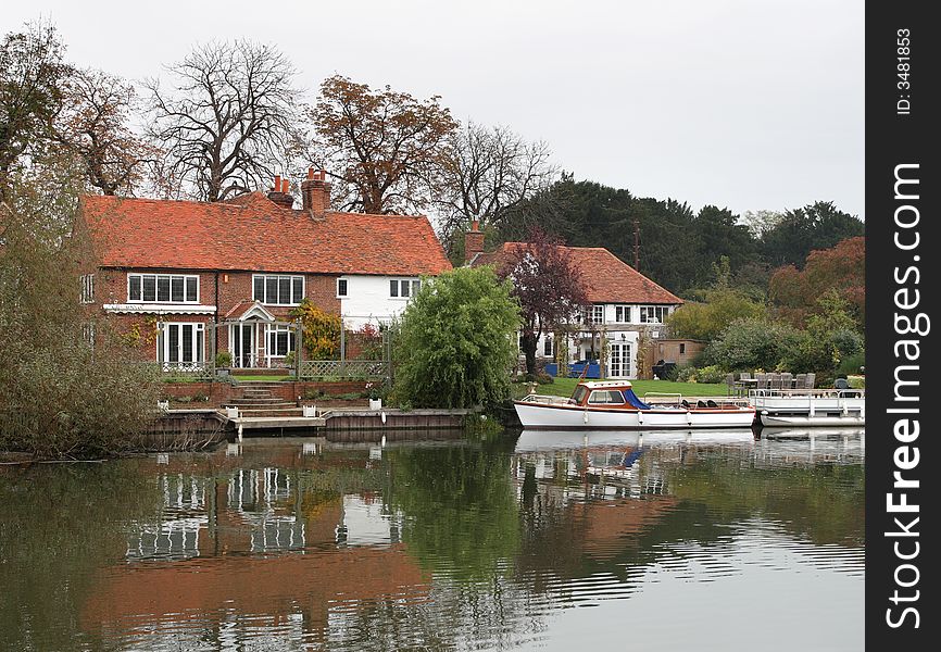 Autumn scene of a House on the Banks of the River Thames in England with a boat moored at the front. Autumn scene of a House on the Banks of the River Thames in England with a boat moored at the front