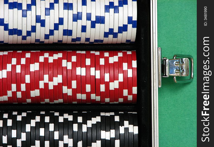 A close up on poker chips arranged inside a carrying case. Three rows with white, red and black chips.