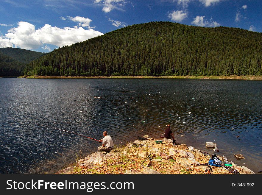 Two men fishing in a polluted lake in Romania. Full of PET s, papers, oils and so on . Two men fishing in a polluted lake in Romania. Full of PET s, papers, oils and so on ...