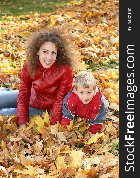 Mother and child sit among fallen leaves. Mother and child sit among fallen leaves