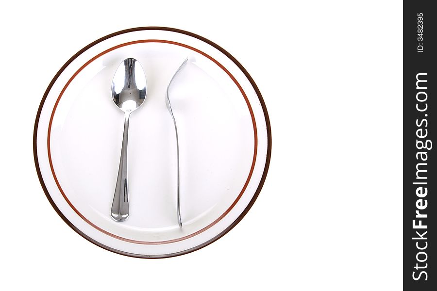 Odd position of fork turn back on spoon placed on a dinner plate. Odd position of fork turn back on spoon placed on a dinner plate