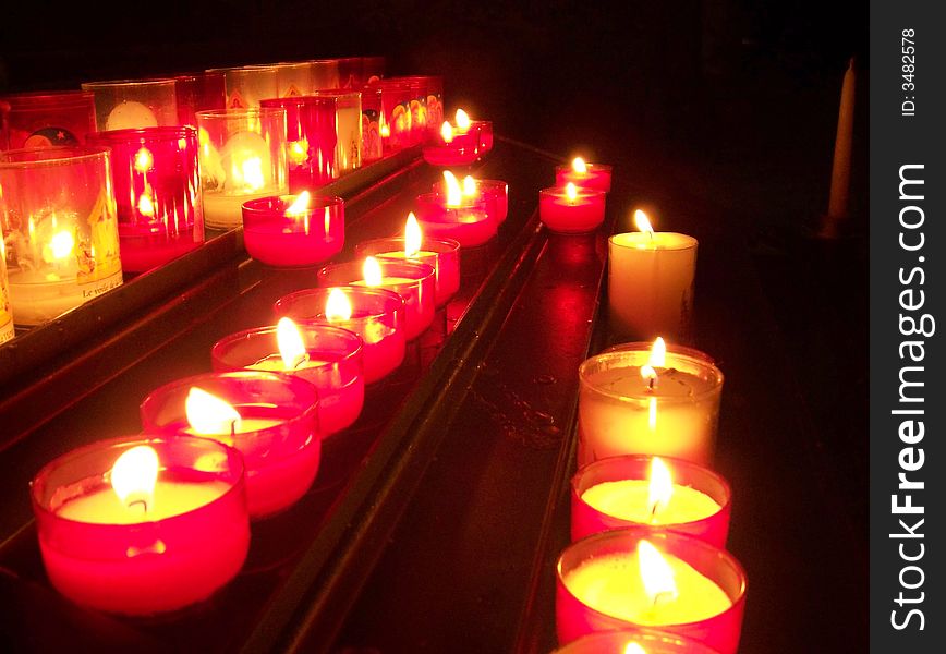 Row of burning candles stacked in a dark room. Row of burning candles stacked in a dark room