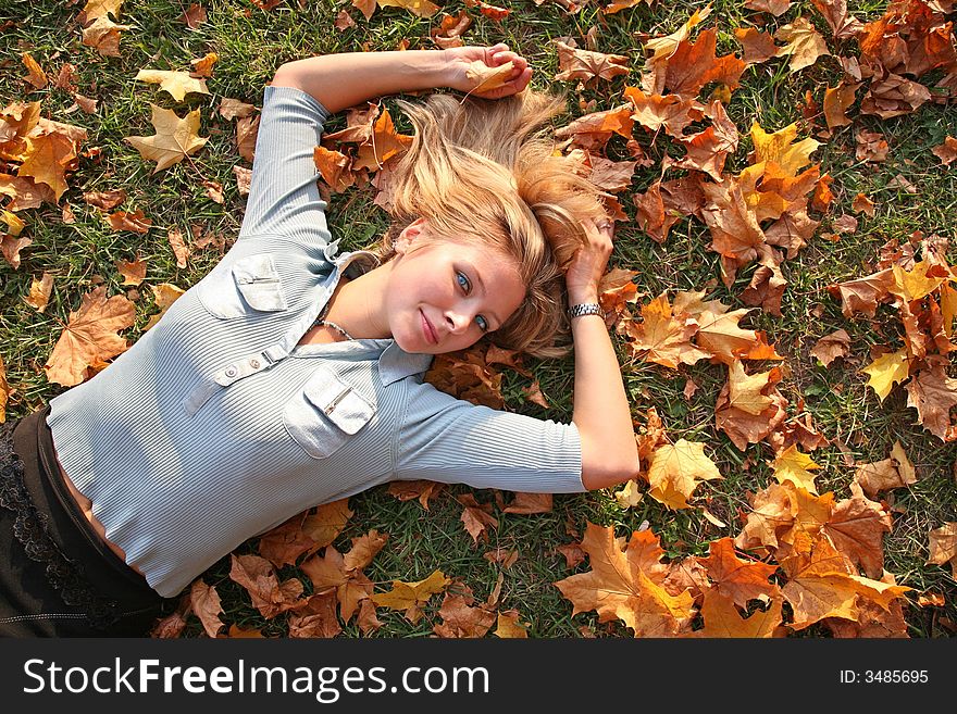 Blue-eyed blond lies among yellow leaves. Blue-eyed blond lies among yellow leaves