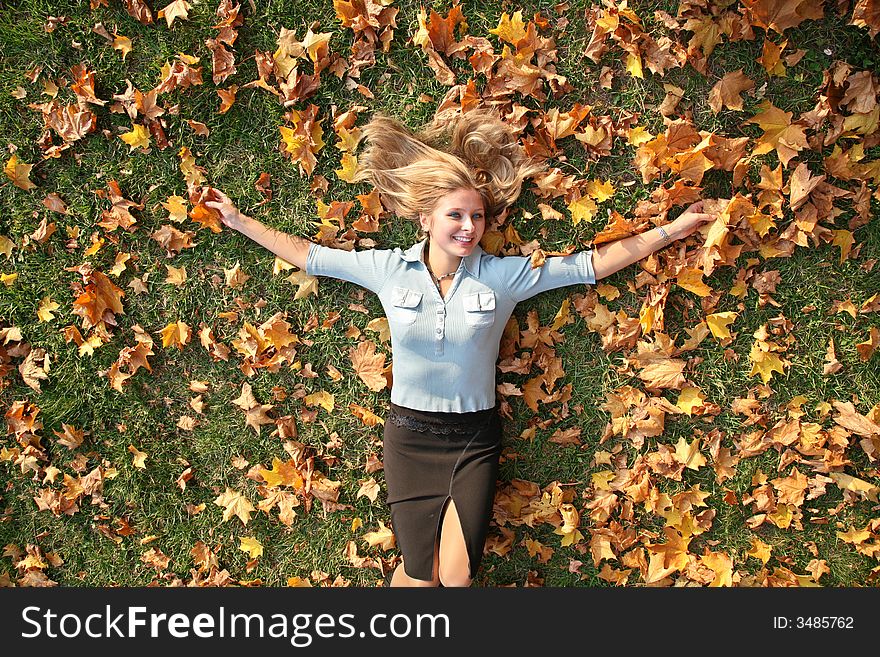 Blue-eyed blond lies among yellow leaves. Blue-eyed blond lies among yellow leaves