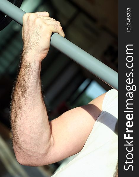 One hand held close a Yoke / Biceps in contraction / Exercises in the gym / Blur Dark Background. One hand held close a Yoke / Biceps in contraction / Exercises in the gym / Blur Dark Background