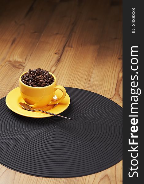 Yellow coffee cup filled with beans on a wooden table