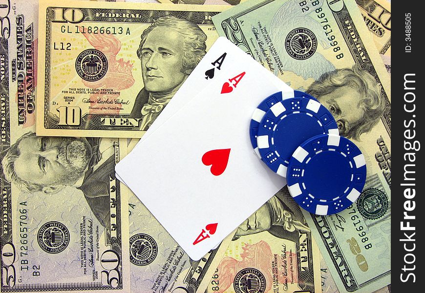 A pair of ace cards and three blue poker chips  over a background formed by bills of us dollars. A pair of ace cards and three blue poker chips  over a background formed by bills of us dollars