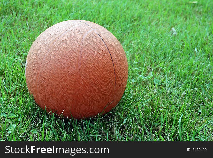 Photo of solitary basket ball sitting on grass outdoors. Photo of solitary basket ball sitting on grass outdoors.