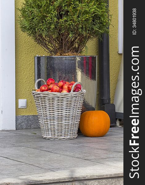 Apples in a basket with a pumpkin on the steps outside the building. Apples in a basket with a pumpkin on the steps outside the building