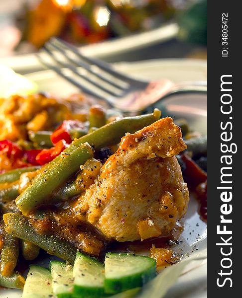 Chicken with green beans and tomatoes served on a white plate. Chicken with green beans and tomatoes served on a white plate