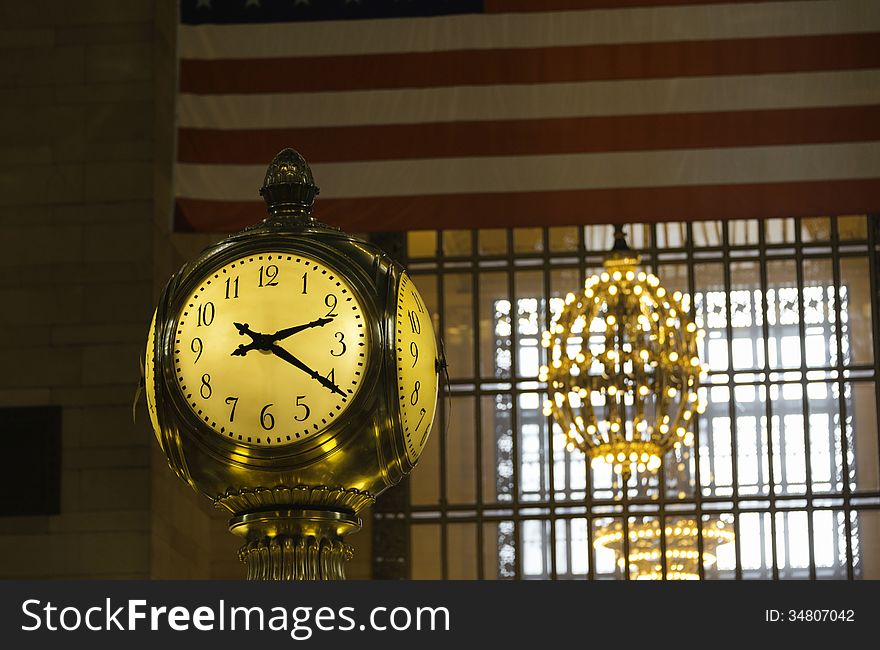 Detail of the antique gold clock over the Information Booth at Grand Central Station in New York City, with partial American flag in the background. Detail of the antique gold clock over the Information Booth at Grand Central Station in New York City, with partial American flag in the background.