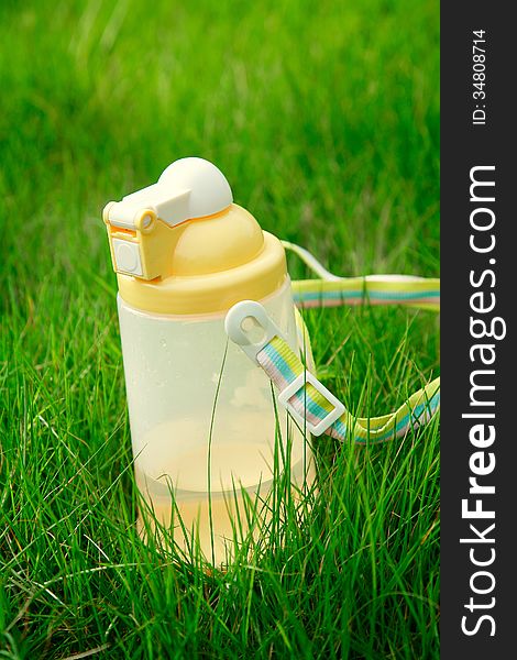 A plastic children kettle with water on grass. A plastic children kettle with water on grass